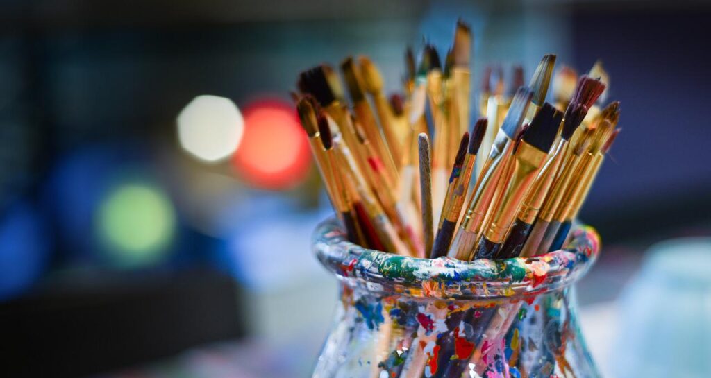 brushes in a glass covered in paint